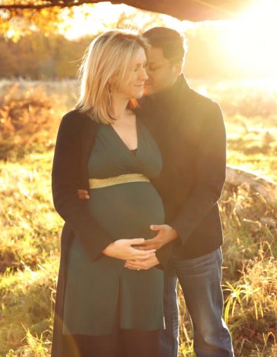 Ania Chandra maternity photographer in Berkshire and beyond. Beautiful photo of pregnant mama and her husband during sunset in Richmond's Park in London . During sunset