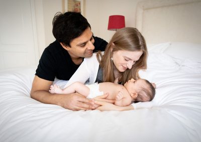 ania chandra newborn photographer based in reading area - parents with newborn baby looking at their san and holding him